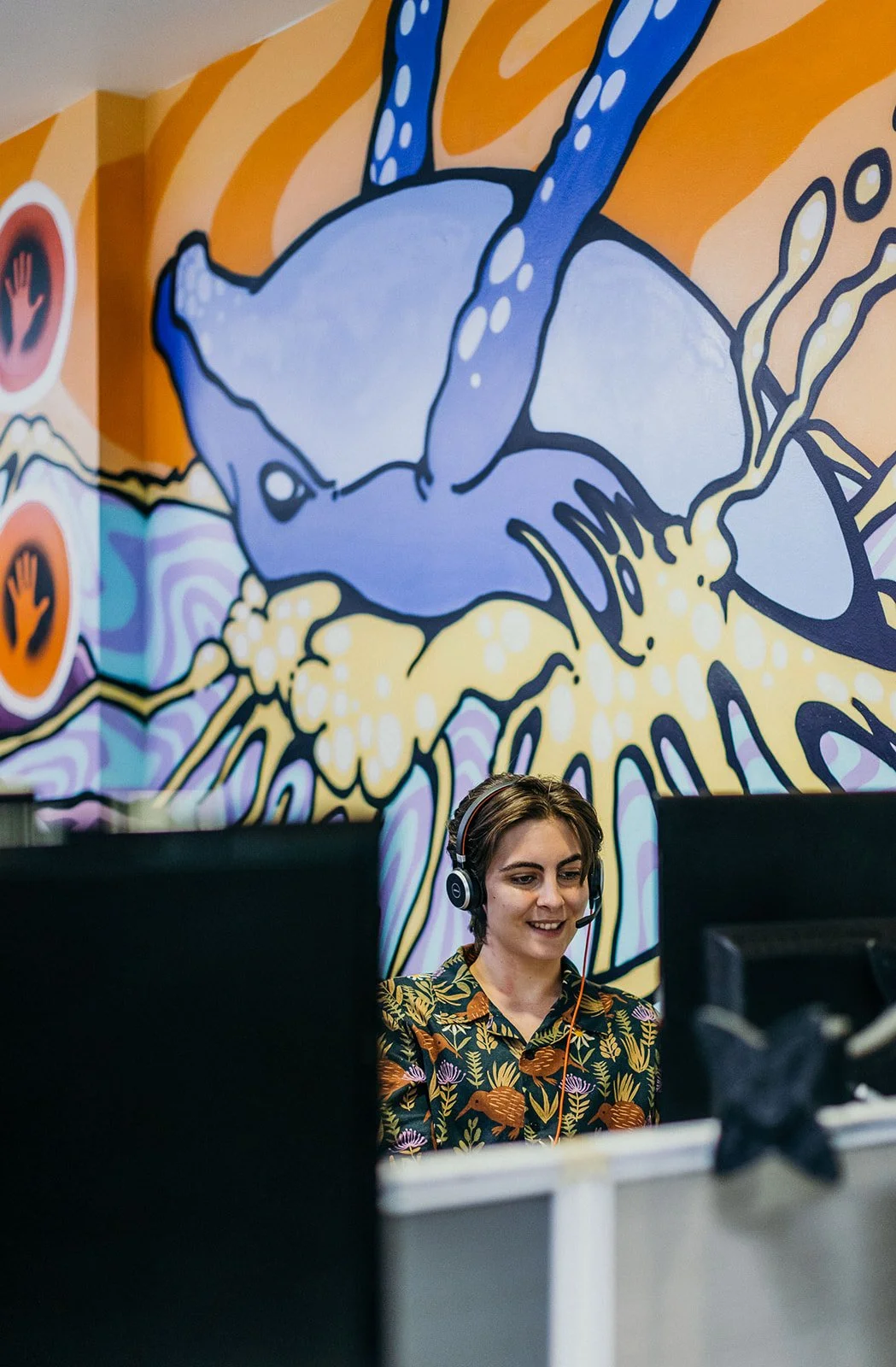 Team member speaking with a headset in a colourful office
